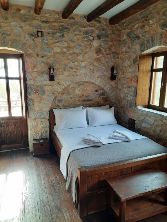 a bedroom with a bed in a stone wall at Studio Tsiliviani in Loukádhika