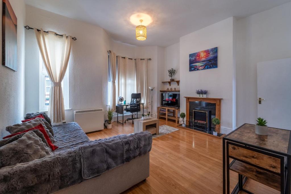 a living room with a couch and a fireplace at Cosmopolitan Comforts Flat in Coventry