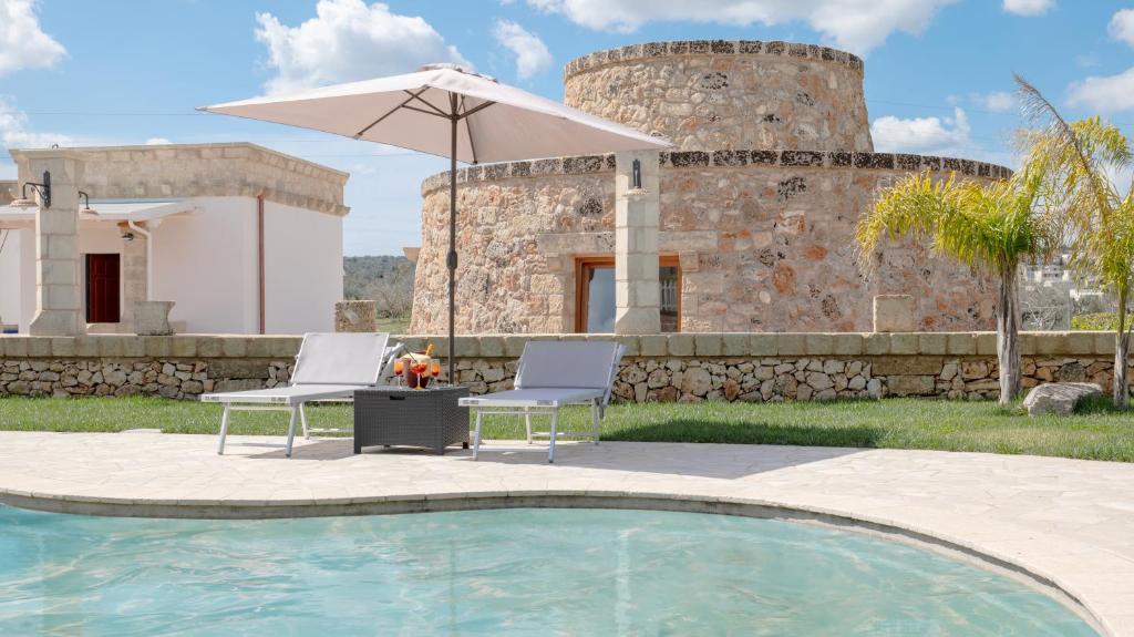 a patio with two chairs and an umbrella next to a pool at Borgo Specchia Natural Resort in Specchia