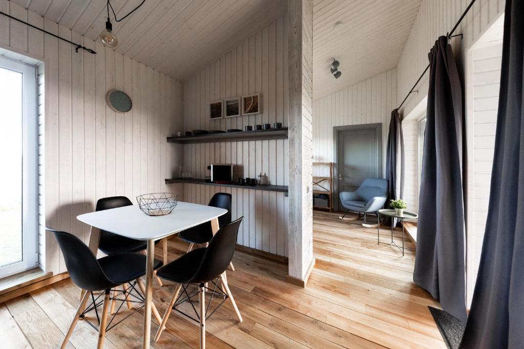 Un comedor con una mesa y sillas blancas. en Ganu Māja, en Užava