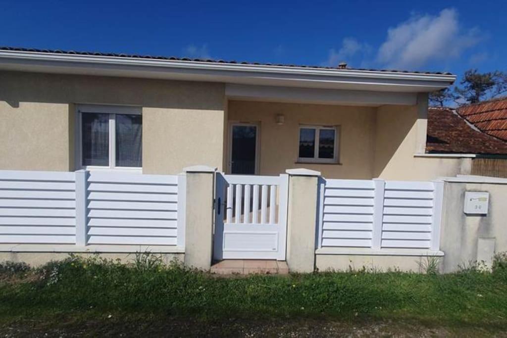 une clôture blanche devant une maison dans l'établissement Maison proche de la plage - 0971, à Vendays-Montalivet