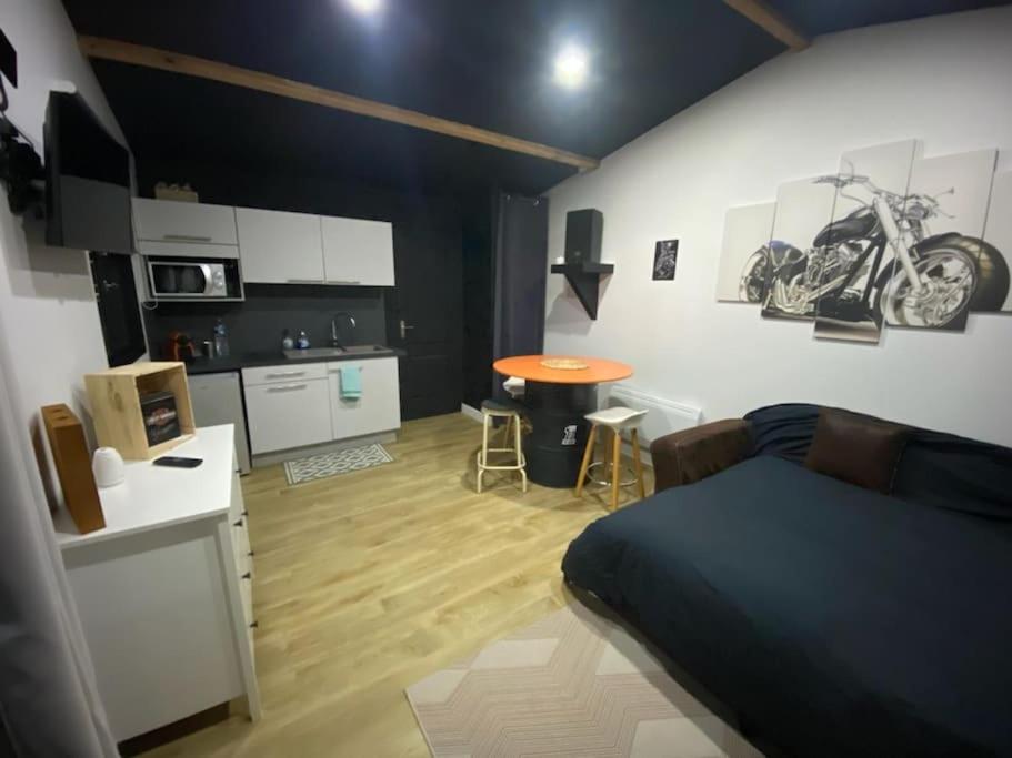een kamer met een bed en een keuken met een motor aan de muur bij Studio style biker avec parking fermé in Izon