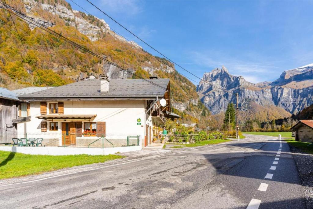 a house on a road with mountains in the background at Le Gîte des Cascades in Sixt