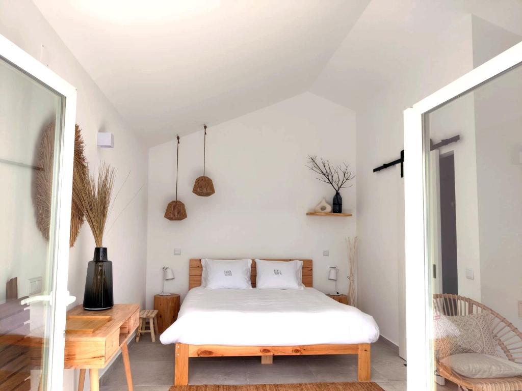 1 dormitorio con cama blanca y mesa de madera en Quinta do Alento, en Sesimbra