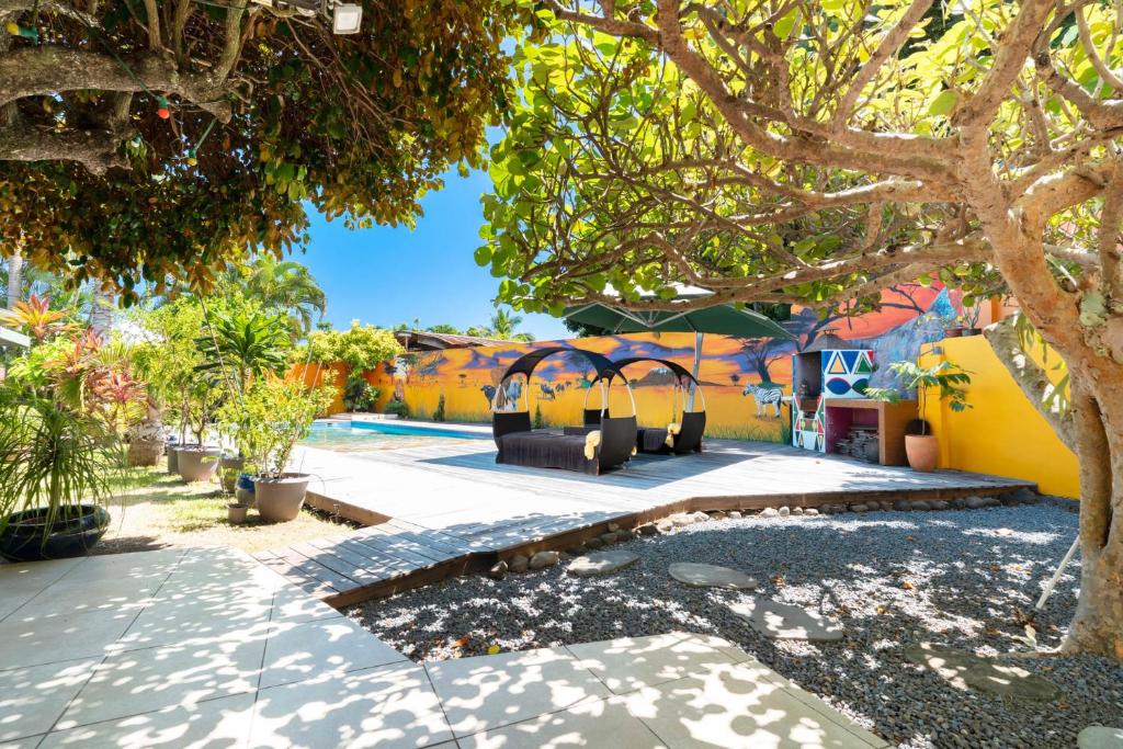 a pool with a group of chairs under a tree at Maison d'invités dans jardin tropical avec piscine à Tahiti in Atiue