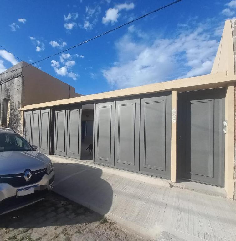 a building with gray doors and a car parked in front at Junidep - Alquiler Temporario - Deptos Nuevos! in Junín