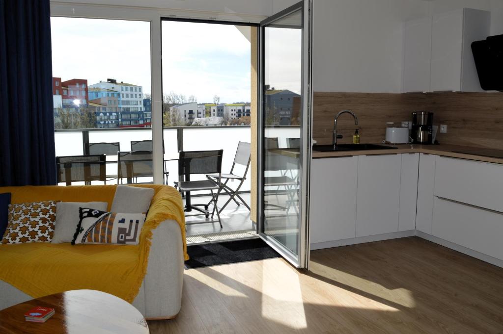 a living room with a couch and a kitchen at Entre Plage et Ports, Le 49 - avec balcon 4 étoiles in Courseulles-sur-Mer