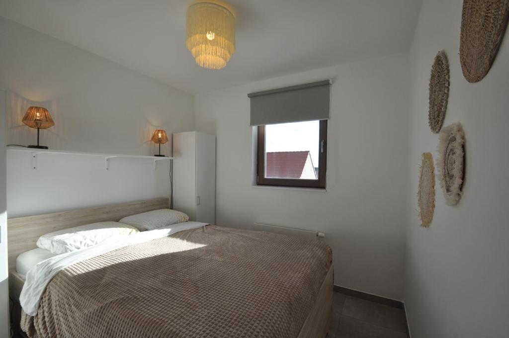 a white bedroom with a bed and a window at De witte oase 22 in Oostduinkerke