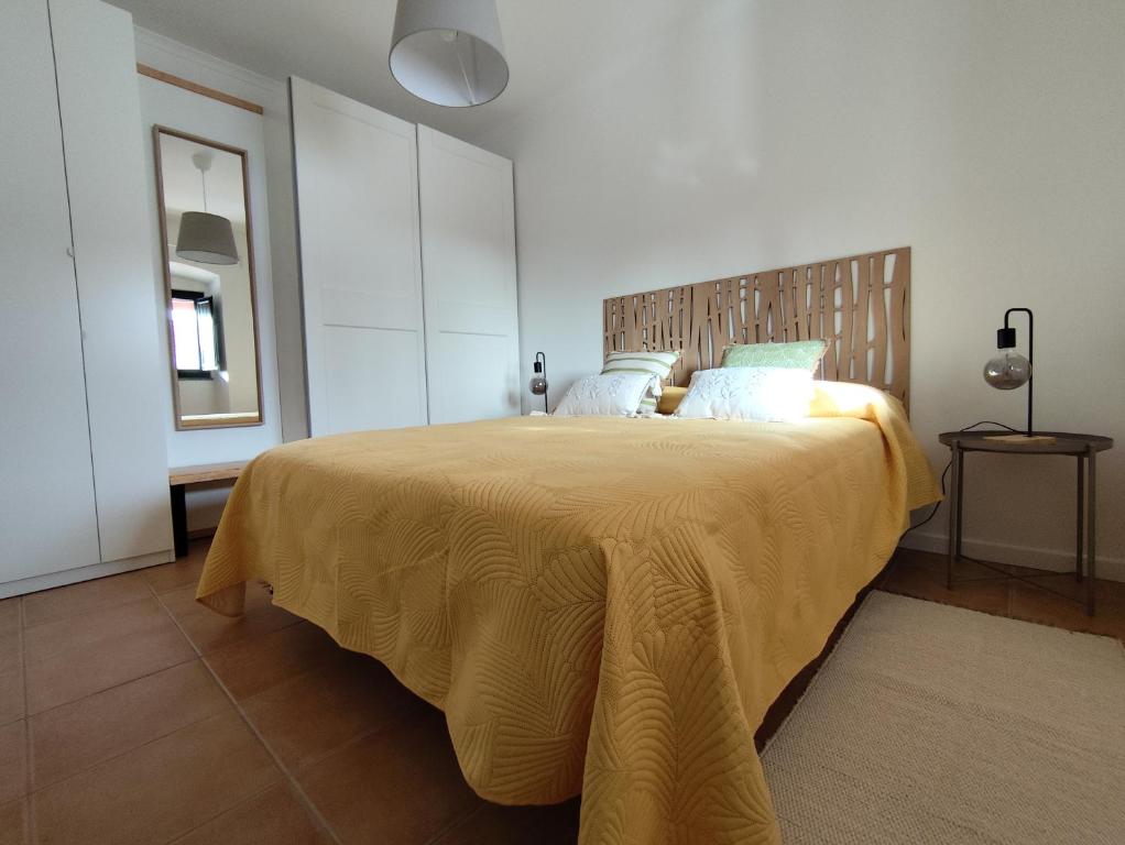 een slaapkamer met een groot bed en een gele deken bij Vila Nova Guest House in Mértola