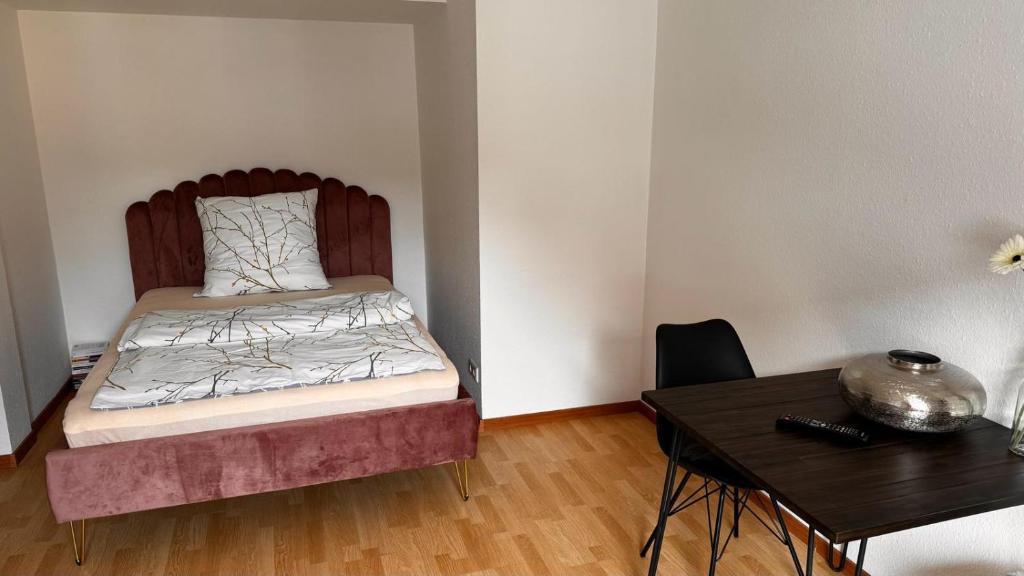 a small bedroom with a bed and a table at Apartment 29 Marienplatz Strohberg in Stuttgart