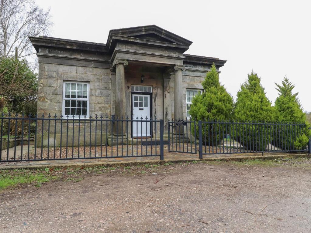 uma velha casa de pedra com uma cerca preta em The Lodge House em Lancaster