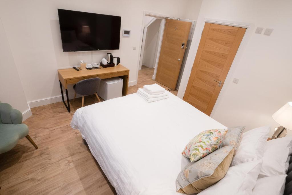 a bedroom with a bed and a desk and a television at The Avonmore Olympia in London
