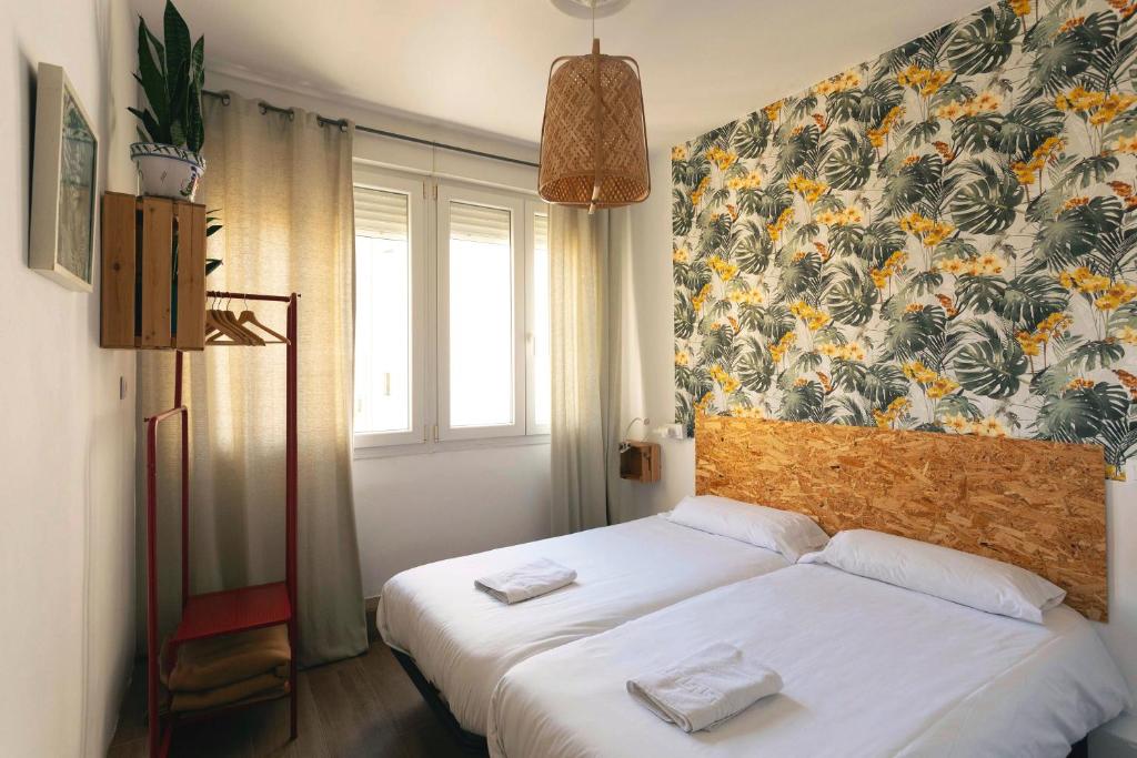 a bedroom with two beds and a floral wall at Green Hostel Oviedo in Oviedo