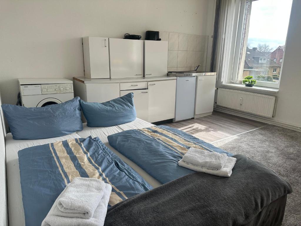 Cet appartement comprend une chambre avec un lit doté d'oreillers bleus et une cuisine. dans l'établissement One, à Wesselburen