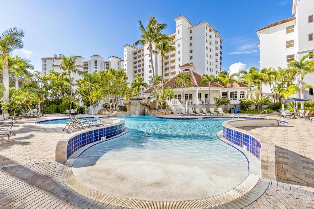 a swimming pool at a resort with palm trees and buildings at Luxury Condo in Regatta in Naples