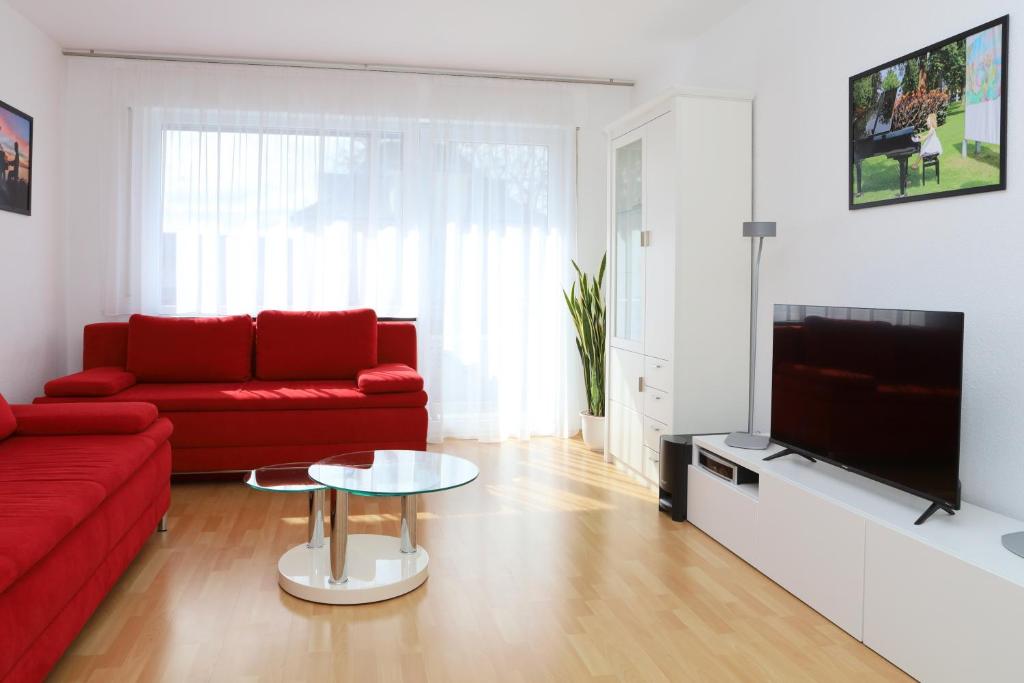 sala de estar con sofá rojo y TV en FeWo Bayha "Im Ort" en Langenargen