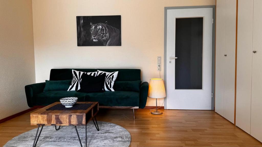 a living room with a green couch and a table at 2 Zimmer Wohnung am Milaneo in Stuttgart