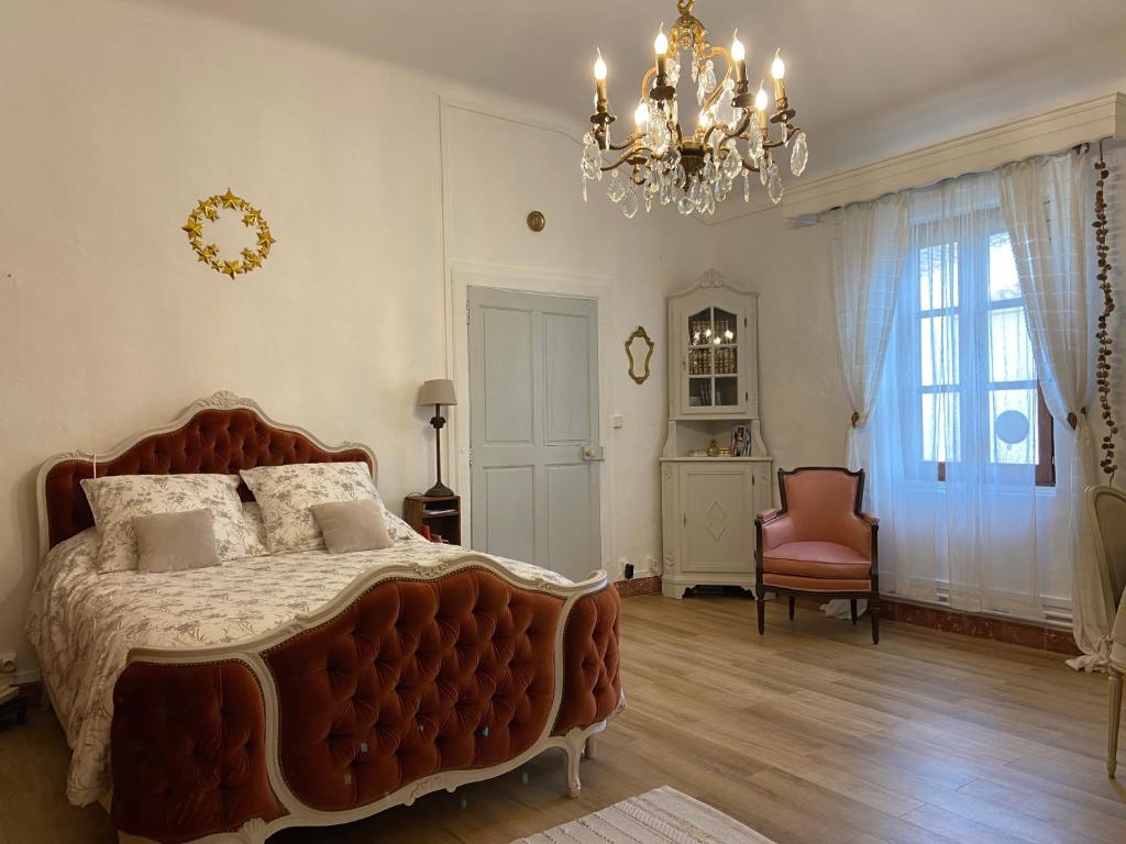 GaronsにあるMaison 1823 - Suites de charme à Garonsのベッドルーム1室(大型ベッド1台、シャンデリア付)