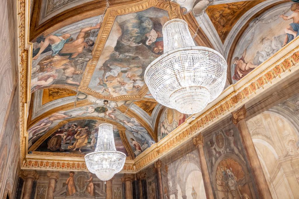 deux lustres suspendus à un plafond orné de peintures dans l'établissement PALAZZO ROMA, à Rome
