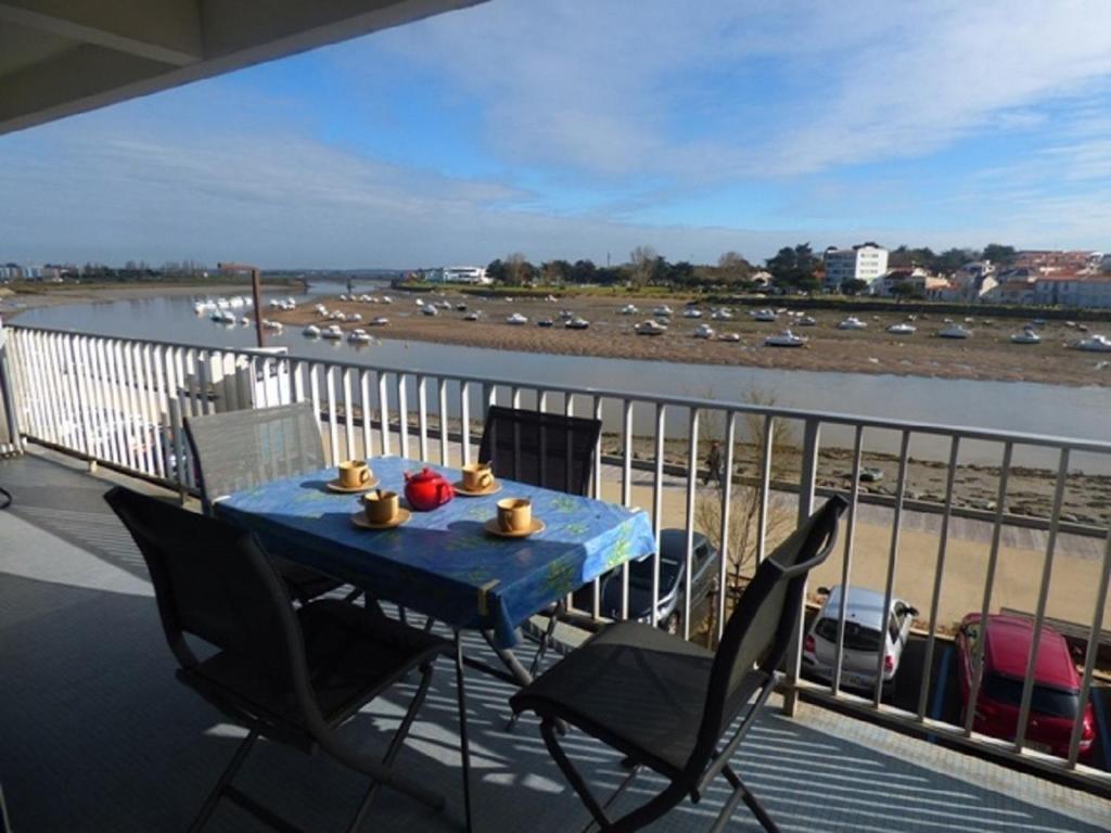 une table et des chaises sur un balcon avec une masse d'eau dans l'établissement Appartement face port pour 4 personnes, à Saint-Gilles-Croix-de-Vie