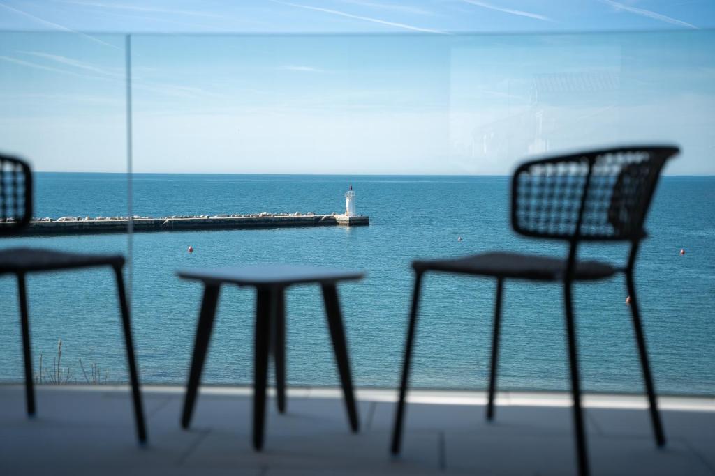 Blick auf das Meer mit Stühlen und einem Leuchtturm in der Unterkunft Blu Mare Hotel in Novigrad Istria