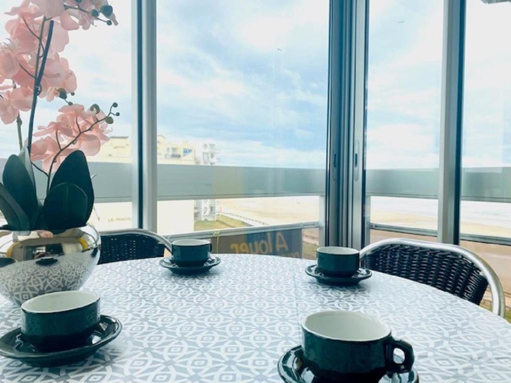 une table avec deux tasses et un vase dessus dans l'établissement L'Amiral, à Saint-Gilles-Croix-de-Vie