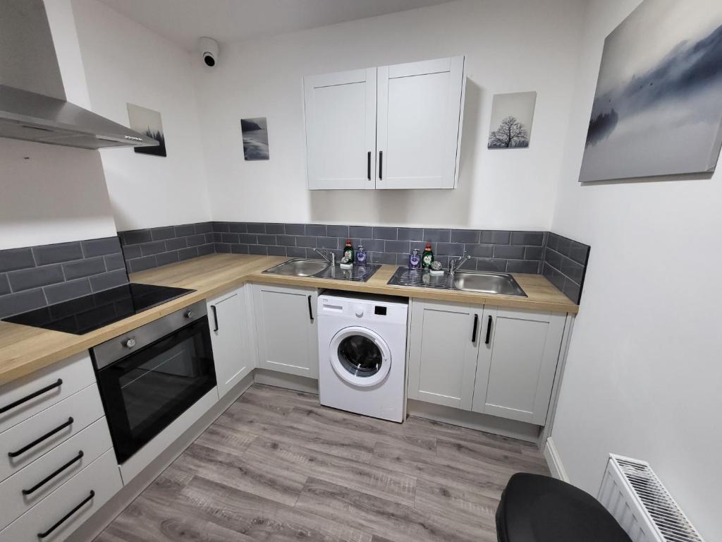 cocina con armarios blancos, lavadora y secadora en Stay Sleep Rest - Alfreton Road en Nottingham