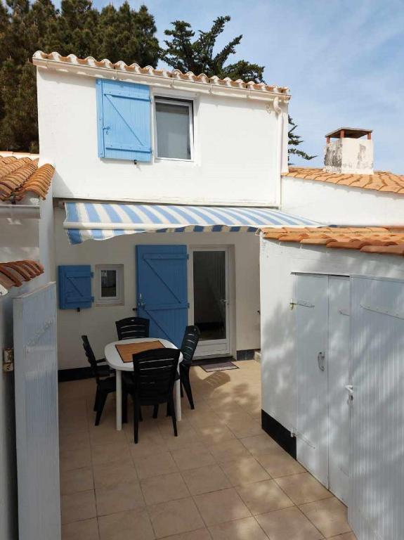 une terrasse avec une table et des chaises ainsi qu'une maison dans l'établissement La Maison Bleue avec piscine, à Bretignolles-sur-Mer
