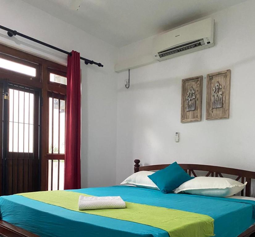 Schlafzimmer mit einem Bett mit blauer und gelber Bettwäsche in der Unterkunft Cinnamon apartment in Panadura