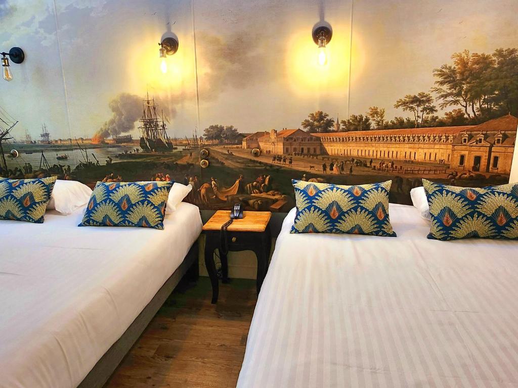 ロシュフォールにあるLogis Hôtel Lafayette Rochefort Franceの壁に絵画が飾られた部屋のベッド2台