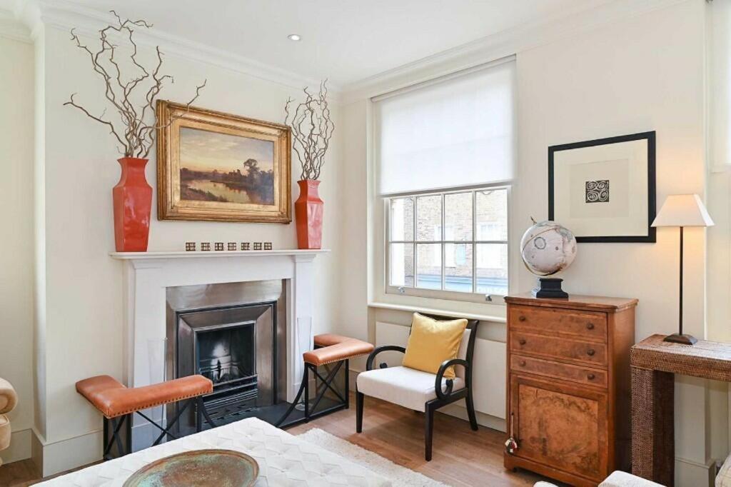 a living room with a fireplace and two chairs at Entire Private Belgravia Mansion - Sleeps 12 in London