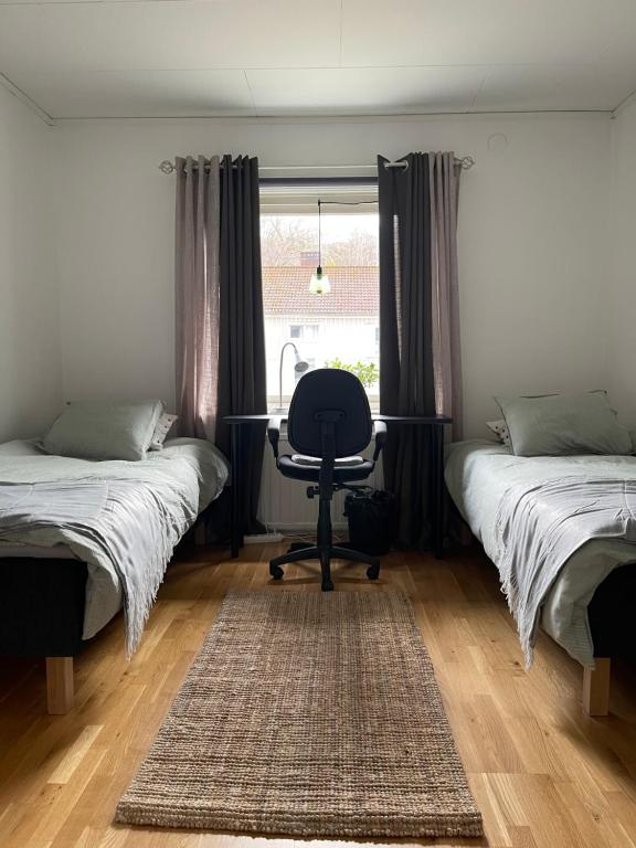 a bedroom with two beds and a chair and a window at Mysig lägenhet, nära det mesta! in Uddevalla