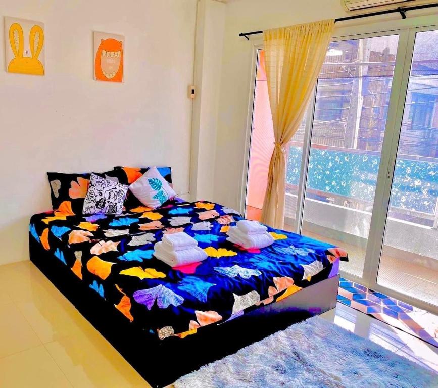a bedroom with a colorful bed with a window at เดอะซันเซ็ท บางแสน in Chon Buri