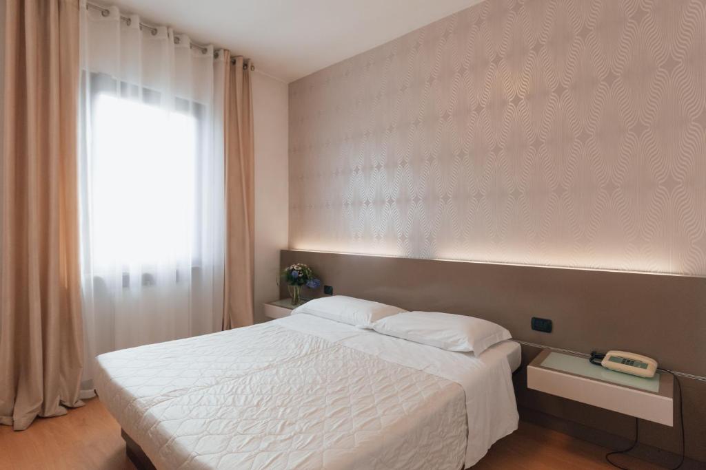 1 dormitorio con cama blanca y ventana en Hotel Gattopardo en Dossobuono