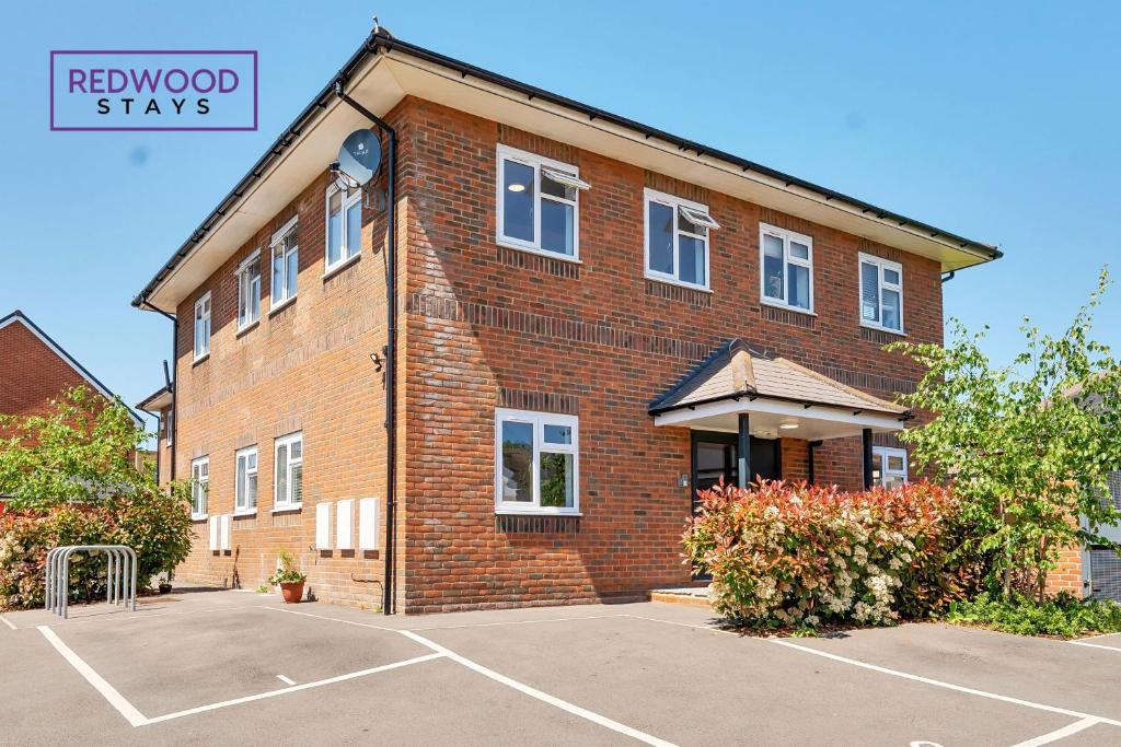 a brick building with a parking lot in front of it at BRAND NEW Serviced Apartments For Contractors & Families With FREE Parking, WiFi & Netflix By REDWOOD STAYS in Basingstoke