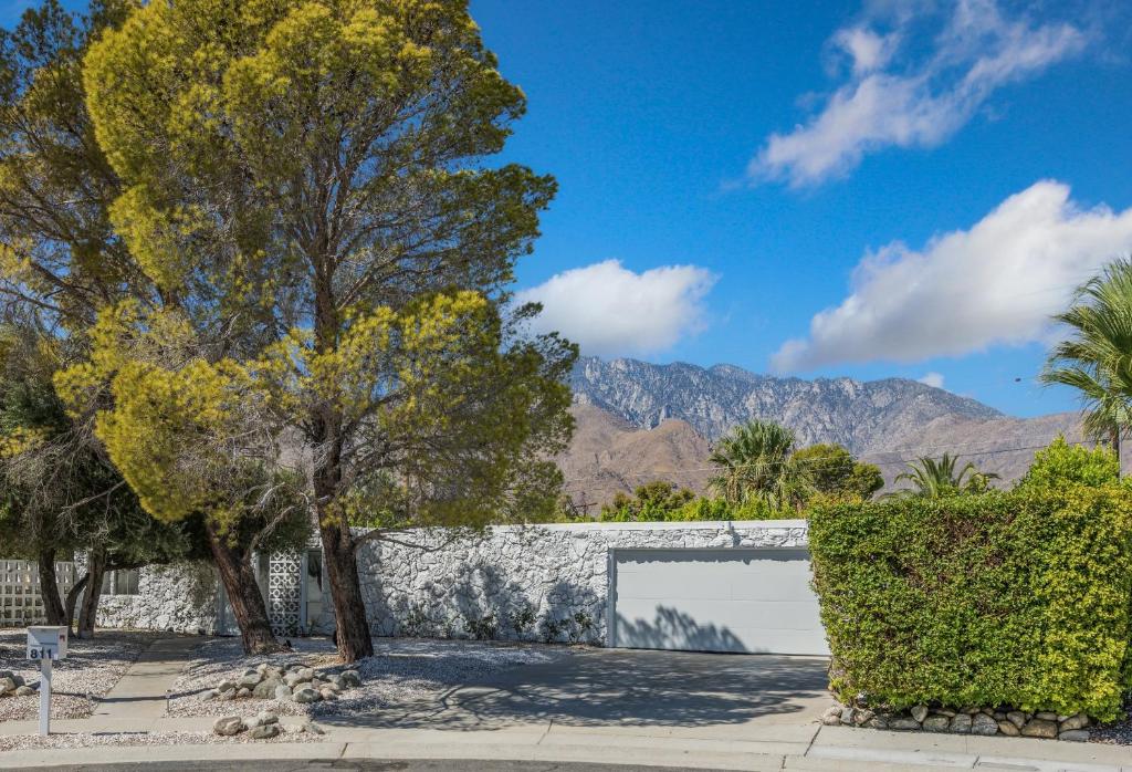 ein Gebäude mit einem Tor, Bäumen und Bergen in der Unterkunft Former Steve McQueen’s home in Palm Springs