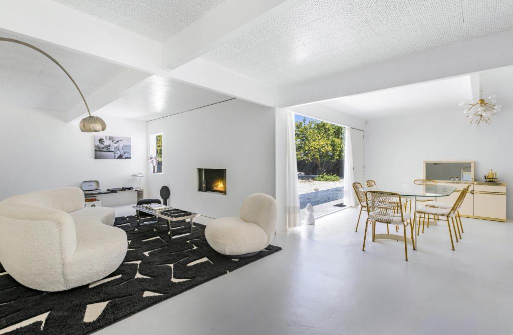 ein Wohnzimmer mit weißen Wänden sowie einem Tisch und Stühlen in der Unterkunft Former Steve McQueen’s home in Palm Springs