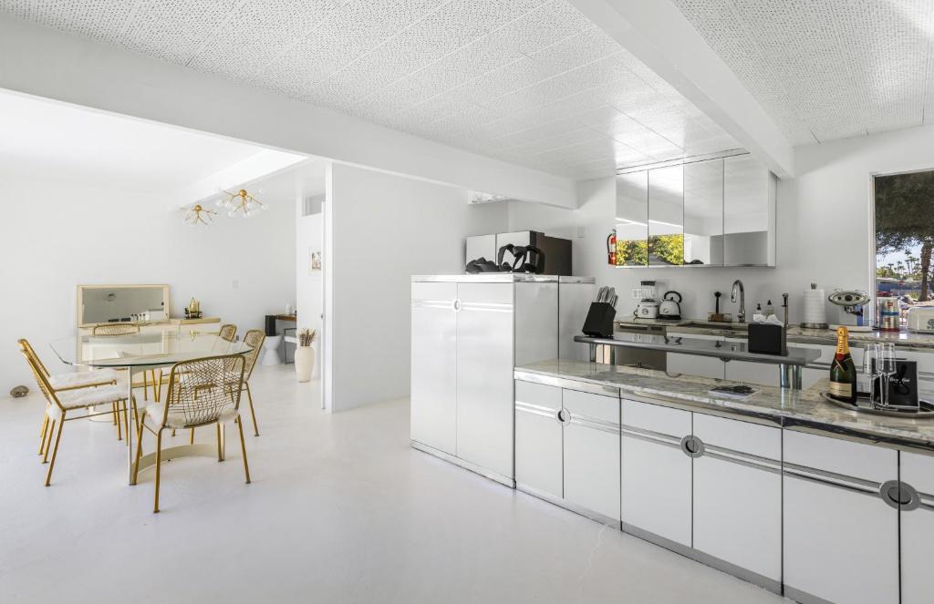 eine Küche mit weißen Schränken und einem Tisch mit Stühlen in der Unterkunft Former Steve McQueen’s home in Palm Springs