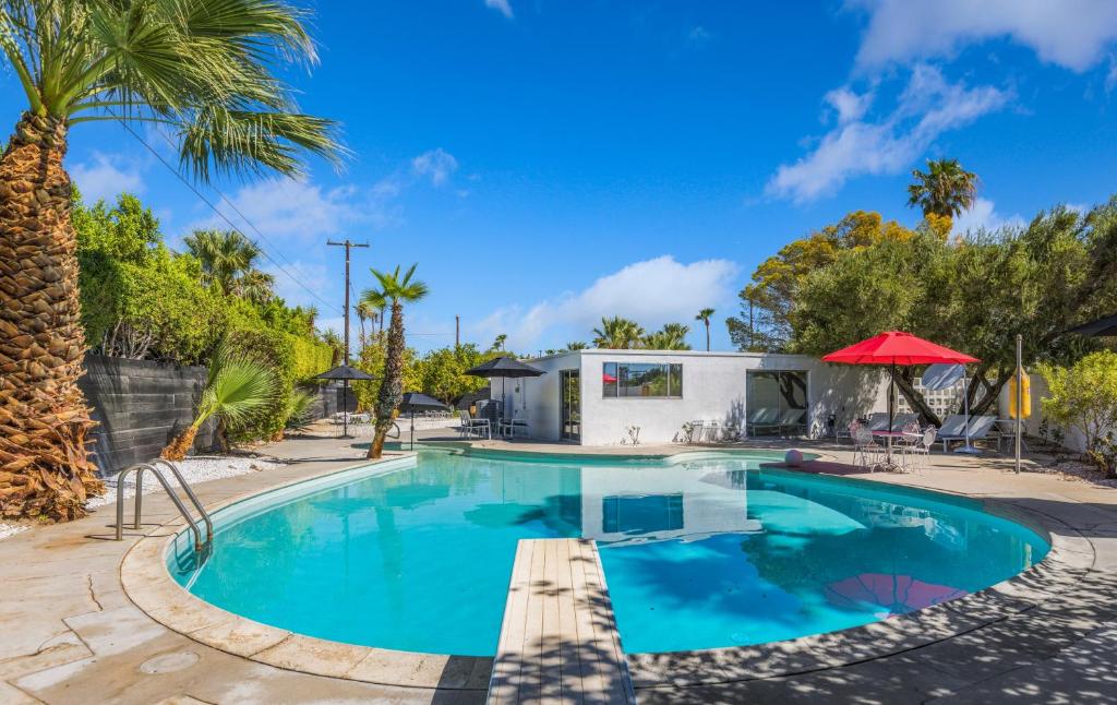 einen Swimmingpool mit Palmen und ein Haus in der Unterkunft Former Steve McQueen’s home in Palm Springs