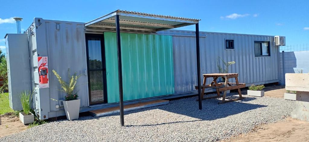 a green tiny house with a wooden bench in front at Alojamientos Dulce Luz in Villa Elisa