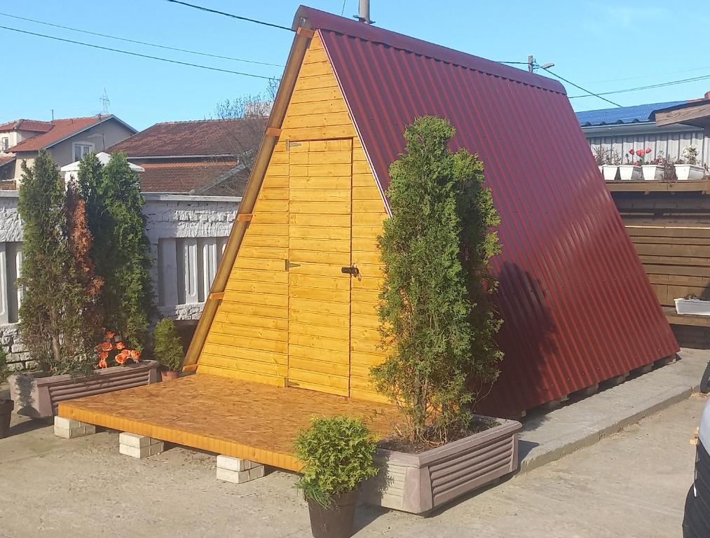 ein gelbes Haus mit einer Bank und einigen Pflanzen in der Unterkunft Glamping Sajlovo in Novi Sad