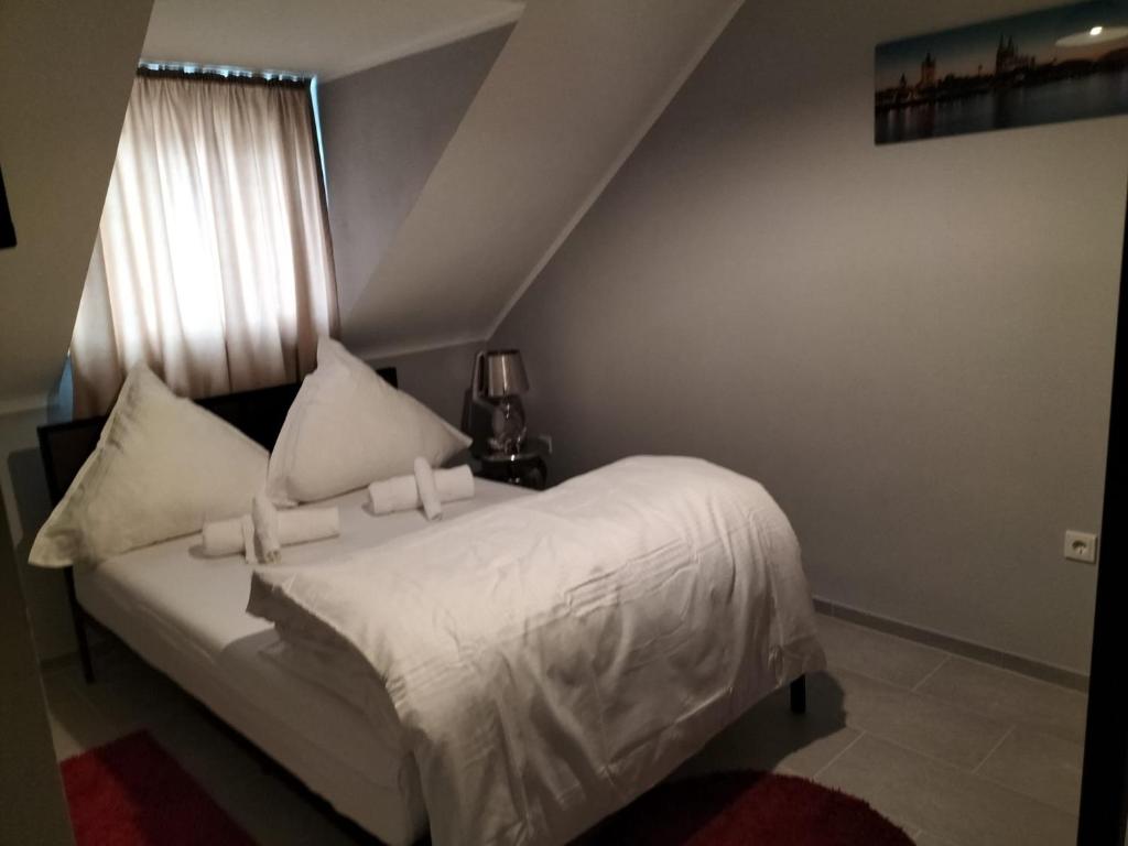 een slaapkamer met een bed met witte lakens en een raam bij Niehler Hotel in Keulen