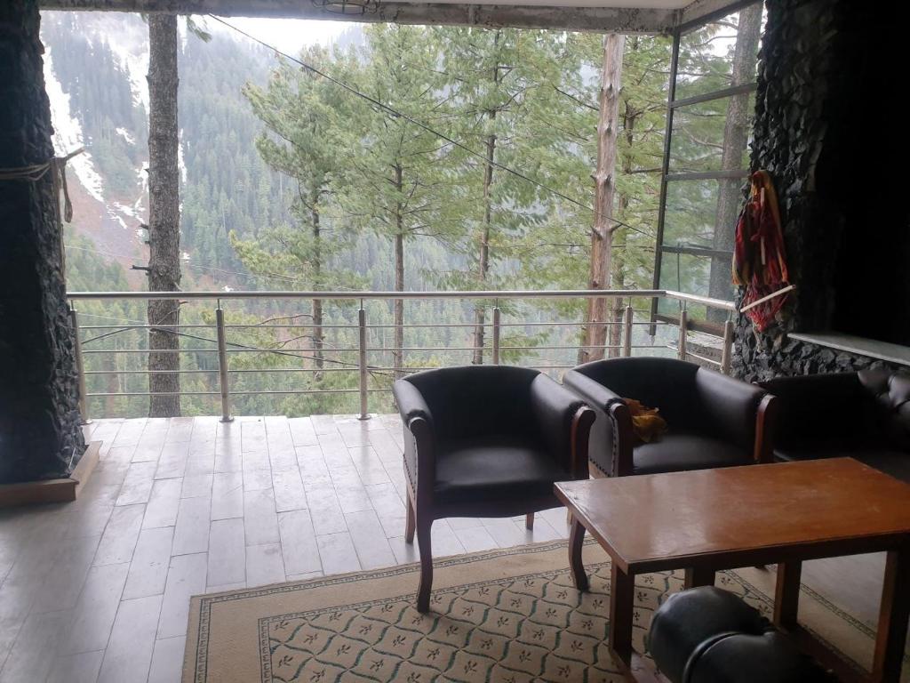a room with a balcony with chairs and a table at Beverly Hills Kuza Gali, Nathiagali District Abbottabad in Abbottabad