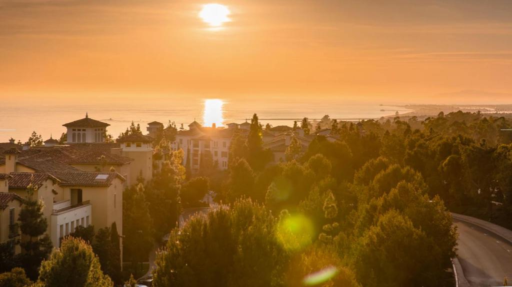 una puesta de sol sobre una ciudad con un edificio y árboles en The Exclusive Marriott's Newport Coast Villas, en Newport Beach