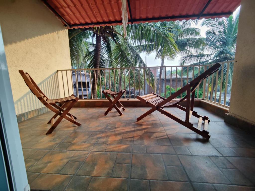 2 Stühle auf einem Balkon mit einer Palme in der Unterkunft Stays4you in Baga
