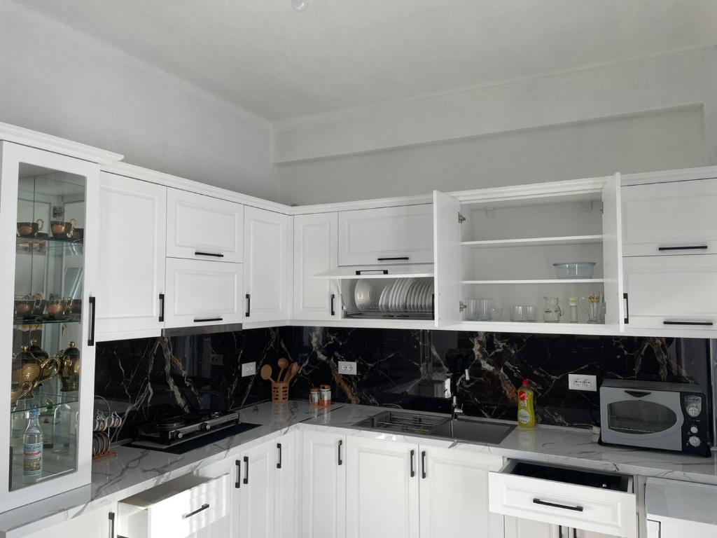 una cucina bianca con armadi bianchi e forno a microonde di Villa71 a Pogradec