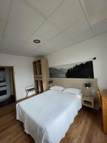 a bedroom with a large white bed with two pillows at Hôtel Le National in Saint-Étienne