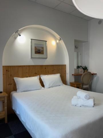 1 dormitorio con 1 cama blanca y 2 toallas en Hôtel Le National, en Saint-Étienne