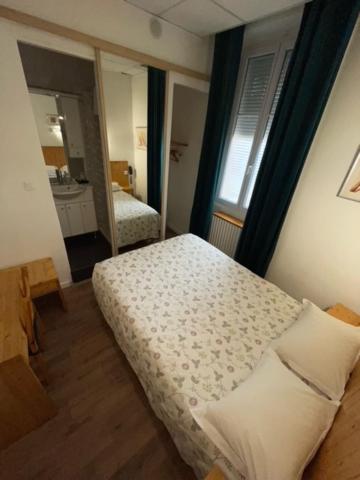 a small bedroom with a bed and a mirror at Hôtel Le National in Saint-Étienne