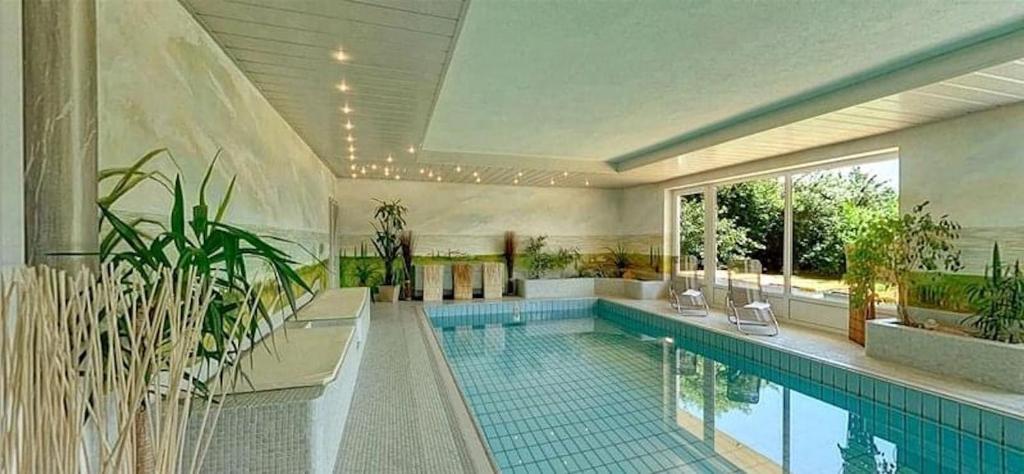 een groot zwembad met planten in een gebouw bij Villa Martini Boutiquehotel in Velden am Wörthersee